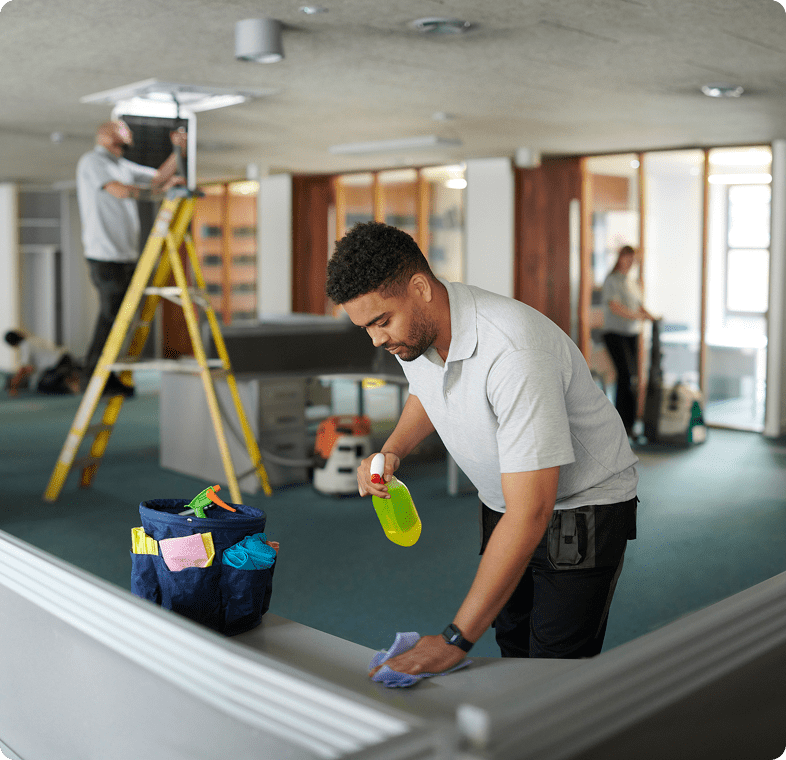 Two workers renovating a room, one painting and one on a ladder.